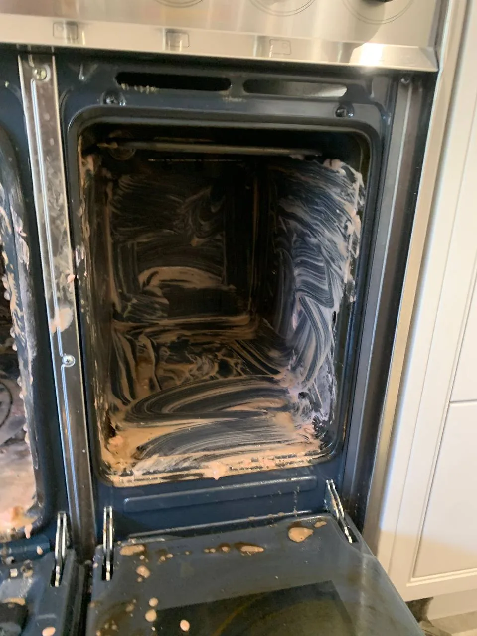 Oven cavity with cleaning product spread over the walls.