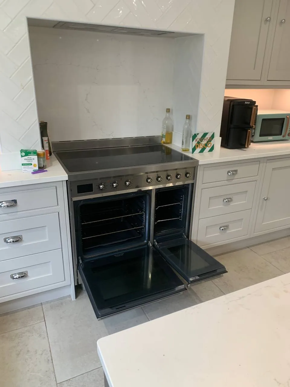 Range cooker with an induction hob and two ovens, both doors open and the ovens clean.