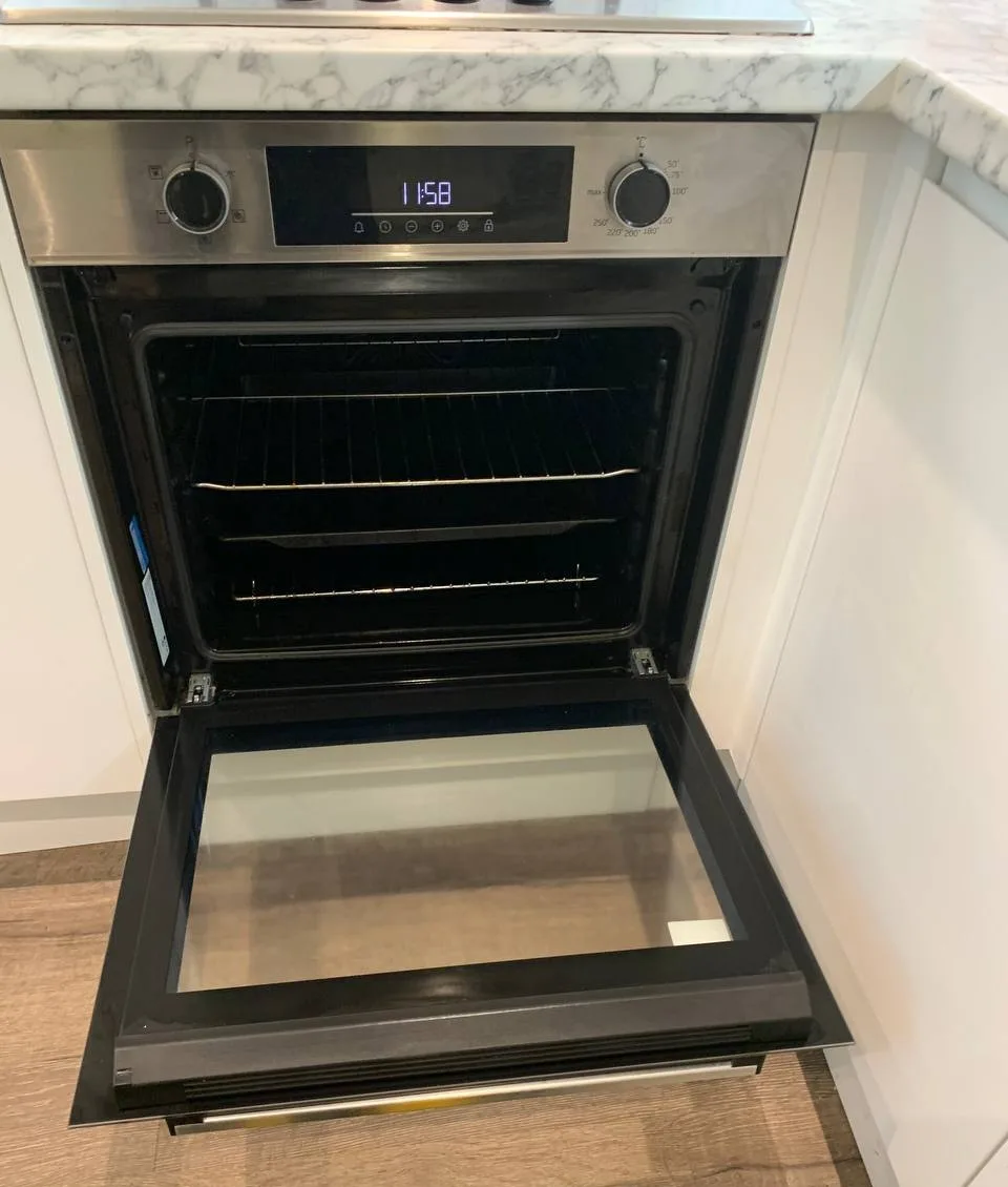 Built-in oven with the door open, showing clean racks and clear door glass.