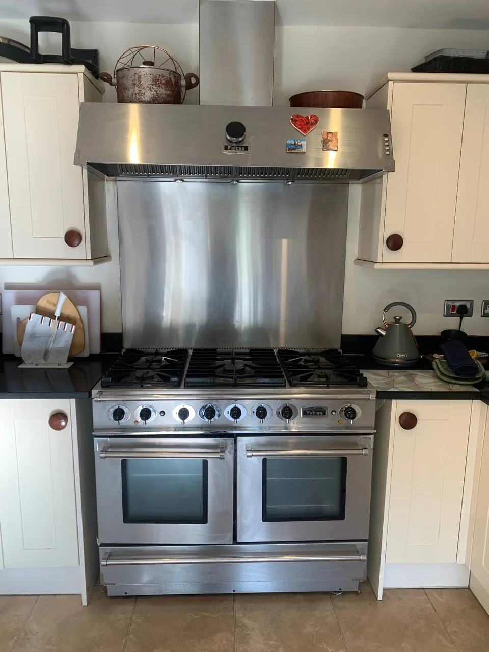 Range cooker with a stainless steel splashback and extractor above it.